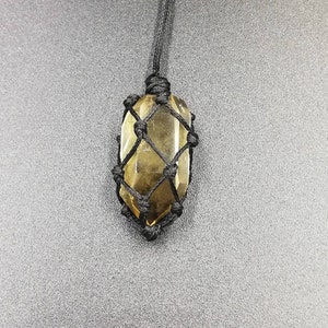 May include: A brown crystal point pendant in a black macrame knot necklace.