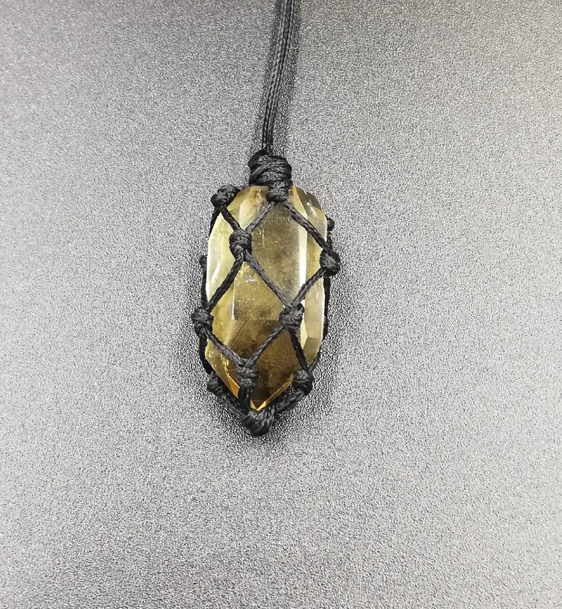 May include: A brown crystal point pendant in a black macrame knot necklace.