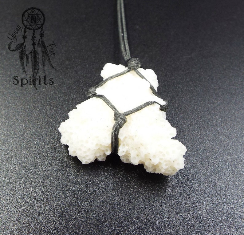 May include: White coral pendant tied with black cord, hanging from a black cord necklace. The coral is a natural, organic shape.