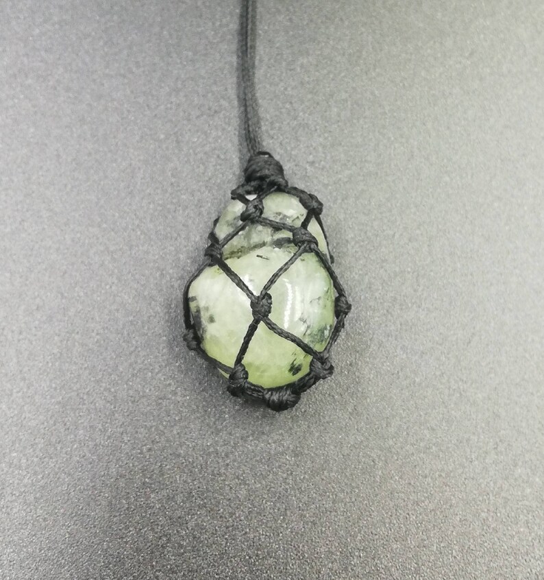 May include: A green gemstone pendant in a black macrame knot necklace.