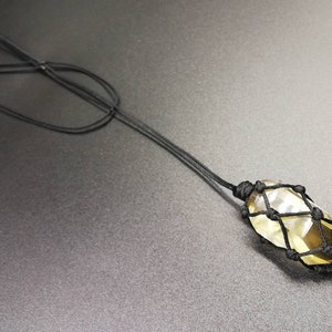 May include: A yellow crystal pendant encased in a black macrame knot necklace.