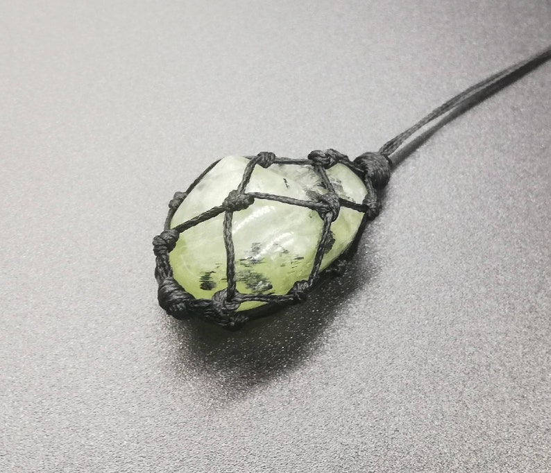 May include: A green crystal stone wrapped in a black macrame knot pendant.