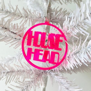 May include: A pink round Christmas ornament with the text "HOUSE HEAD" in white lettering.