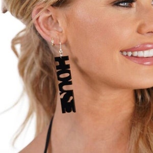 May include: Black acrylic earrings with the word "HOUSE" spelled vertically.