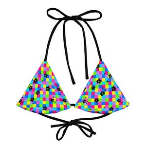 May include: A black bikini top with adjustable straps. The top is made of a colorful fabric with a checkered pattern and black flowers.