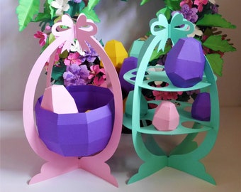 Könnte beinhalten: Eine farbenfrohe Osterdekoration mit papiergefertigten eiförmigen Körben und einem mehrstöckigen Ständer. Die Dekoration umfasst einen rosa Korb, einen mintgrünen Ständer und geometrische Papiereier in Lila, Rosa und Gelb. Im Hintergrund ein Blumenkranz.
