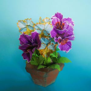 May include: A terracotta pot with a cluster of purple and white pansies. The pansies have a yellow center and are arranged in a bouquet.