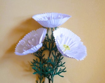 May include: Three white paper flowers with green stems and leaves. The flowers are made from cupcake liners and have a delicate, ruffled appearance.