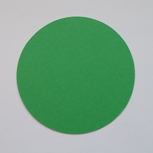 May include: A solid green circle made of paper.