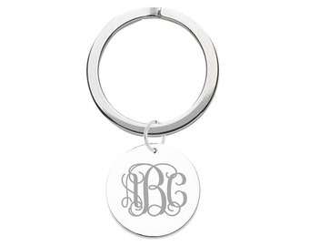May include: Silver key chain with a round charm featuring a monogrammed design with the letters "B C" in a script font.