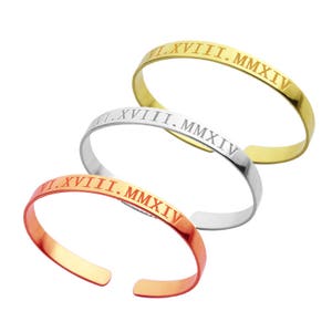 May include: Three bangle bracelets in gold, silver, and copper with the inscription "VI.XVIII.MMXIV" on each.