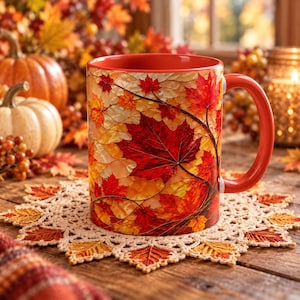 May include: A ceramic mug featuring a vibrant autumn leaf pattern in shades of red, orange, and yellow. The mug has a solid orange interior and a matching orange handle, showcasing a detailed design of maple leaves across the exterior surface.