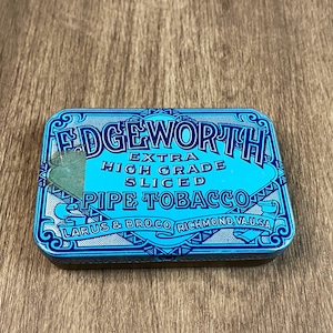 May include: A blue and white tin with the text "Edgeworth Extra High Grade Sliced Pipe Tobacco Larus & Bro. Co. Richmond, Va. U.S.A."