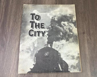 May include: A vintage book cover titled To The City featuring a black and white photograph of a steam locomotive emitting a large plume of dark smoke against a cloudy sky. The text To The City is printed in a bold, sans-serif font on the left side.