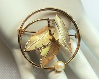 Vintage Polished Gold Tone Circle Pin Brooch with Detailed Textured Gold Tone Leaves and Prong Set Faux Pearl Accent