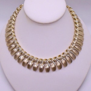 May include: A gold-tone necklace with a chain design and leaf-shaped pendants.
