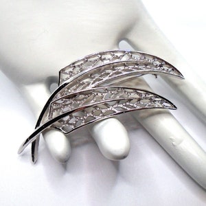 Puede incluir: Un broche de filigrana de plata en forma de dos hojas superpuestas.