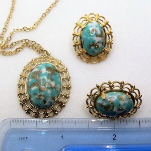 May include: A gold necklace with a turquoise and white oval pendant, and two matching earrings with turquoise and white oval stones.