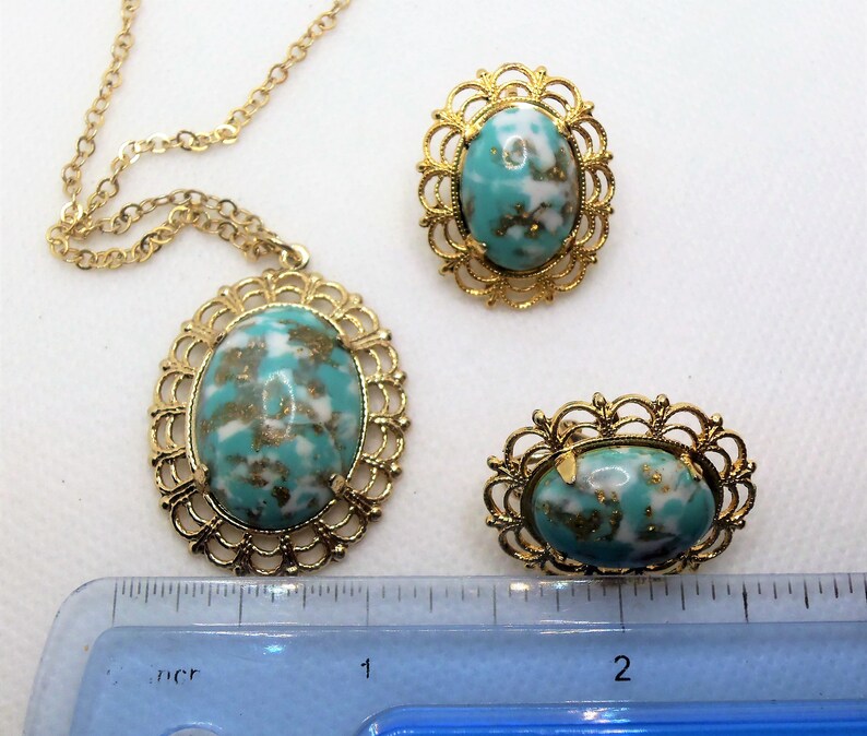 May include: A gold necklace with a turquoise and white oval pendant, and two matching earrings with turquoise and white oval stones.
