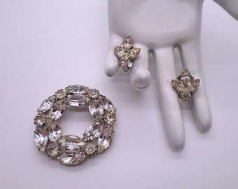 Può includere: Un set di gioielli vintage in strass con una spilla rotonda e un paio di orecchini a clip. Il set è realizzato con strass trasparenti incastonati in metallo color argento.
