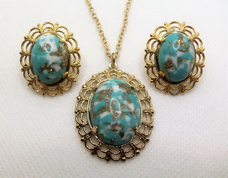 May include: A gold tone necklace and earrings set with turquoise blue and white oval stones in a filigree setting.