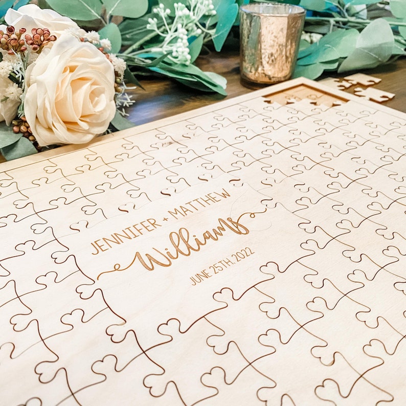 Laser cut wooden puzzle. The parts that connect are shaped like hearts. It is made of 1/8th inch birch wood. The big middle piece has engraved first names, last name and the date. A wood frame is also included along with a sign and the perfect pen.