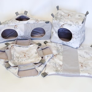 Op de afbeelding: Een set van vijf grijze en witte stoffen speelstructuren voor hamsters of kleine dieren. De structuren omvatten een tunnel, een kubus en drie platforms. De stof heeft een witte achtergrond met een grijs en bruin bloemenpatroon.