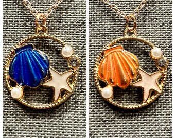 May include: Two gold necklaces with a circular pendant featuring a white starfish and a seashell. One pendant has a blue seashell and the other has an orange seashell.