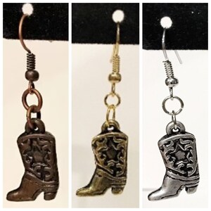 May include: Three pairs of dangle earrings featuring a cowboy boot charm. The boots are available in bronze, gold, and silver.