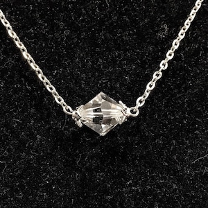 Op de afbeelding: Een zilveren ketting met een heldere kristallen hanger.