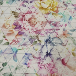 Könnte beinhalten: Ein weißer Stoff mit einem Blumenmuster. Die Blumen sind in den Farben Rosa, Lila, Blau und Gelb gehalten. Der Stoff hat ein geometrisches Muster aus Dreiecken.