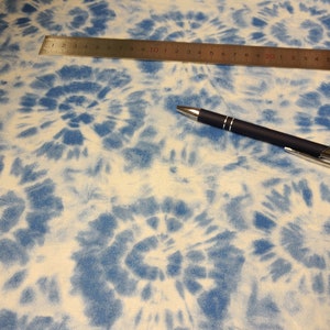 Könnte beinhalten: Blau-weißer Batikstoff mit einem wirbelnden Muster. Der Stoff ist glatt und hat eine weiche Textur.