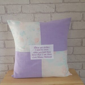 May include: A lavender and white patchwork pillow with a message embroidered on a small white square: "These are clothes I used to wear, when you hold them know that I am there. Love Mama Adelaide."
