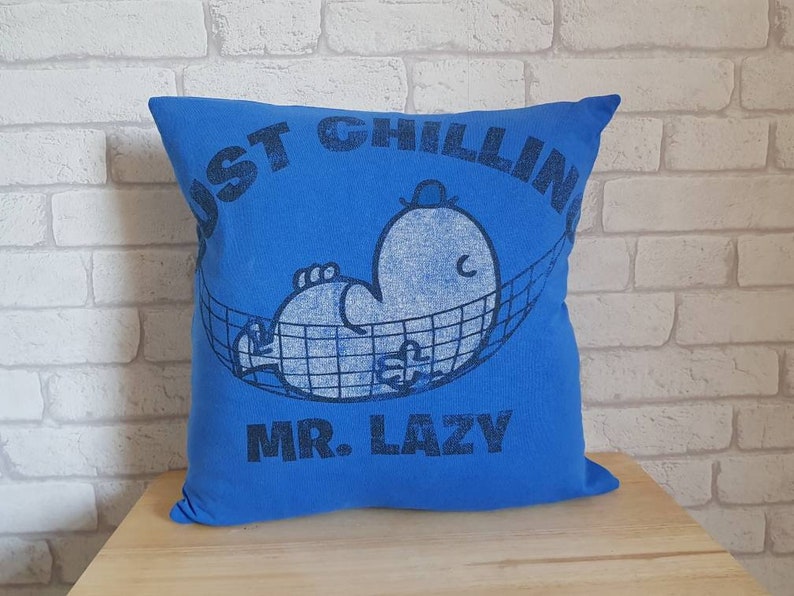 May include: Blue pillow with a white graphic of a cartoon character in a hammock. The text "Just Chillin' Mr. Lazy" is printed on the pillow.