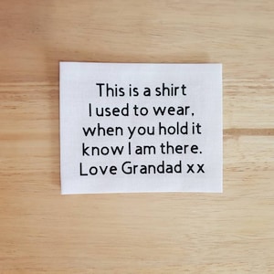 Puede incluir: Cuadrado de tela blanca con texto negro que dice "This is a shirt I used to wear, when you hold it know I am there. Love Grandad xx"