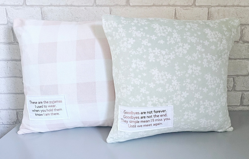 May include: Two decorative throw pillows with sentimental messages. One pillow is white with pink gingham and the other is light green with a white floral pattern. The pillow with the gingham pattern has the text "These are the pajamas I used to wear. When you hold them know I am there." The pillow with the floral pattern has the text "Goodbyes are not forever. Goodbyes are not the end. They simple mean I'll miss you. Until we meet again."