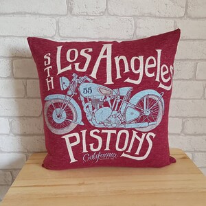 May include: Red throw pillow with a vintage motorcycle graphic and the text "Los Angeles Pistons California Established 1962".