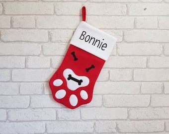 May include: Red and white Christmas stocking with a paw print design and the name "Bonnie" embroidered on the white cuff.