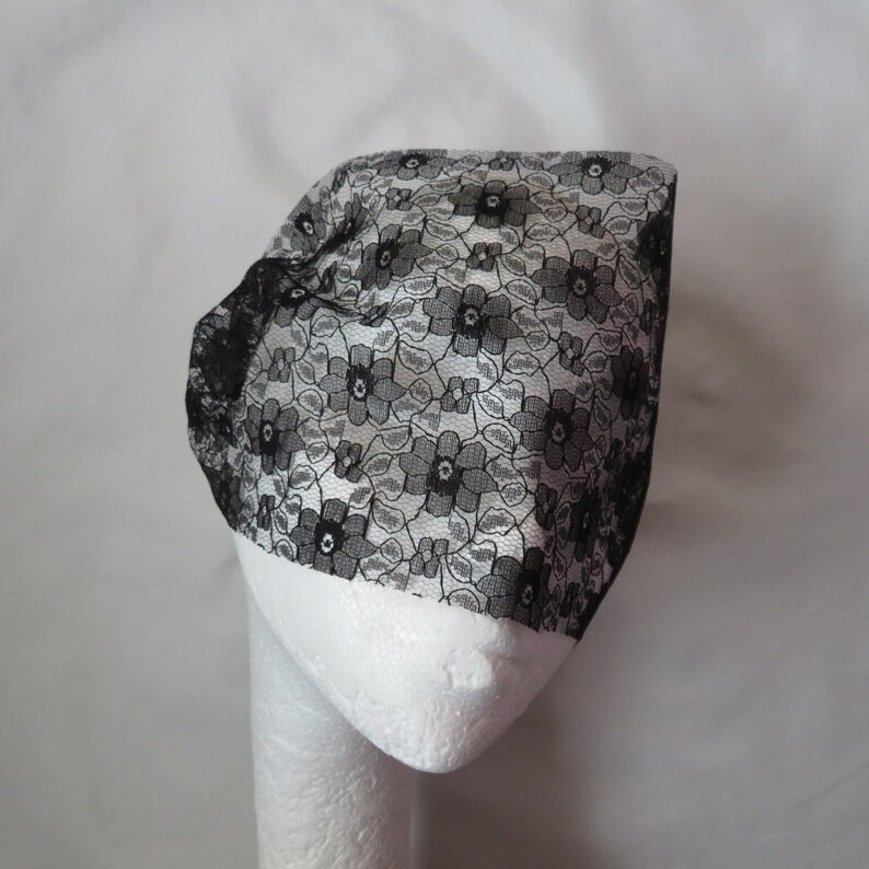 May include: Black lace hair covering with a floral pattern.