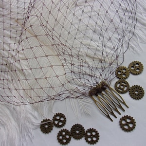 May include: A brown hair comb with a decorative design of small metal gears. The comb is on a white background with white feathers.