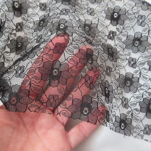 May include: Black lace fabric with a floral pattern. The lace is delicate and has a fine mesh.