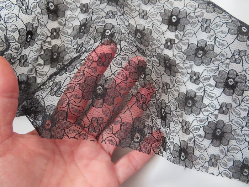 May include: Black lace fabric with a floral pattern. The lace is delicate and has a fine mesh.