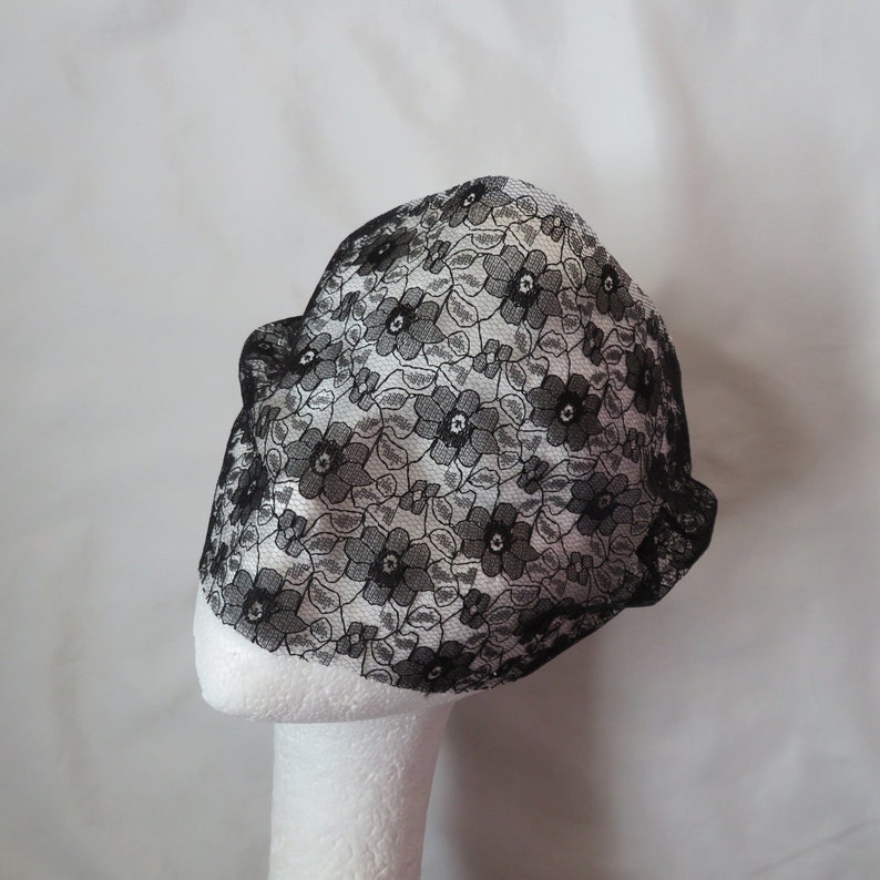May include: Black lace mask with a floral pattern. The mask is on a white mannequin head.
