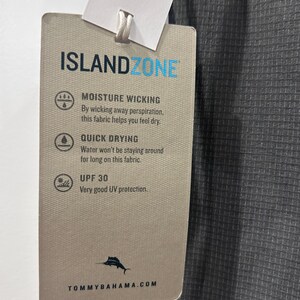May include: A gray fabric tag with the text "ISLANDZONE" in blue. The tag details moisture-wicking, quick-drying, and UPF 30 UV protection properties. The Tommy Bahama logo and website are at the bottom. The fabric is a textured gray.