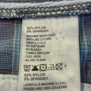 May include: Close-up of a clothing tag with care instructions. The tag lists the fabric composition as 92% nylon and 8% spandex. Washing instructions include machine wash cold with like colors, gentle cycle, no softener, no bleach, tumble dry low, cool iron, and no dry clean.