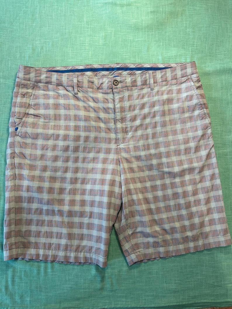 May include: Brown and white plaid shorts with a button closure and belt loops. The shorts have two front pockets and two back pockets. The shorts are made of a lightweight material and are suitable for casual wear.