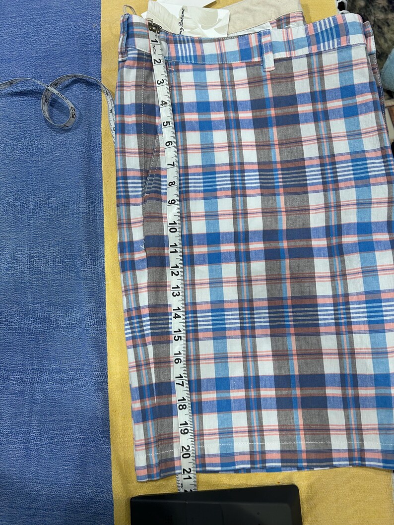 Peut inclure: Shorts &agrave; carreaux bleus, blancs et marron, avec un m&egrave;tre ruban indiquant une longueur de 53 cm. Le short pr&eacute;sente un motif &agrave; carreaux classique et une fermeture &agrave; bouton et fermeture &eacute;clair. Fabriqu&eacute; en tissu l&eacute;ger.
