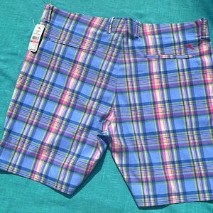 K&ouml;nnte beinhalten: Blaue karierte Shorts mit rosa, gelben und wei&szlig;en Akzenten. Die Shorts haben eine Ges&auml;&szlig;tasche und ein angebrachtes Etikett. Die Shorts sind aus einem leichten Stoff gefertigt, perfekt f&uuml;r warmes Wetter.