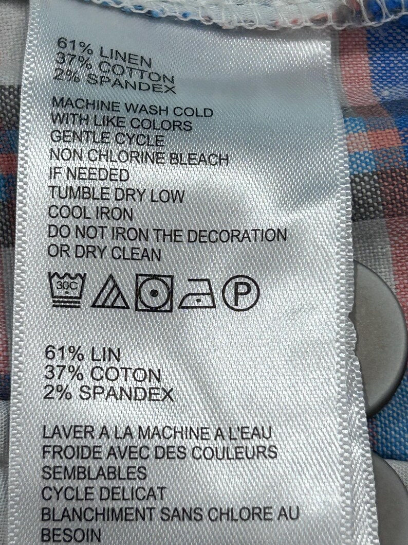 Peut inclure: Gros plan sur une &eacute;tiquette en tissu blanc avec du texte noir. L'&eacute;tiquette indique la composition du tissu : 61% lin, 37% coton et 2% &eacute;lasthanne. Instructions de lavage : lavage en machine &agrave; froid, cycle d&eacute;licat.