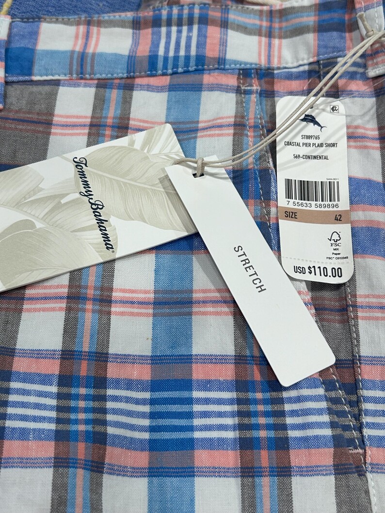Peut inclure: Gros plan d'un short &agrave; carreaux bleu, rose, blanc et gris. Le short porte une &eacute;tiquette avec les mentions "Tommy Bahama" et "STRETCH". La taille est 42.